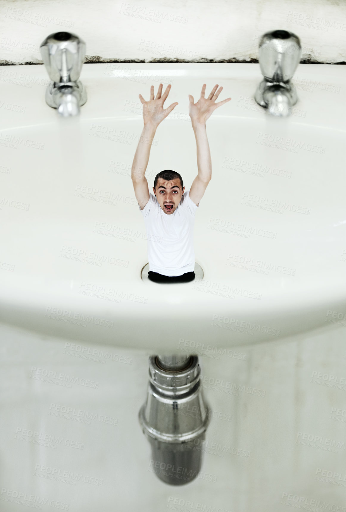 Buy stock photo A young man being sucked down the drain in a giant basin