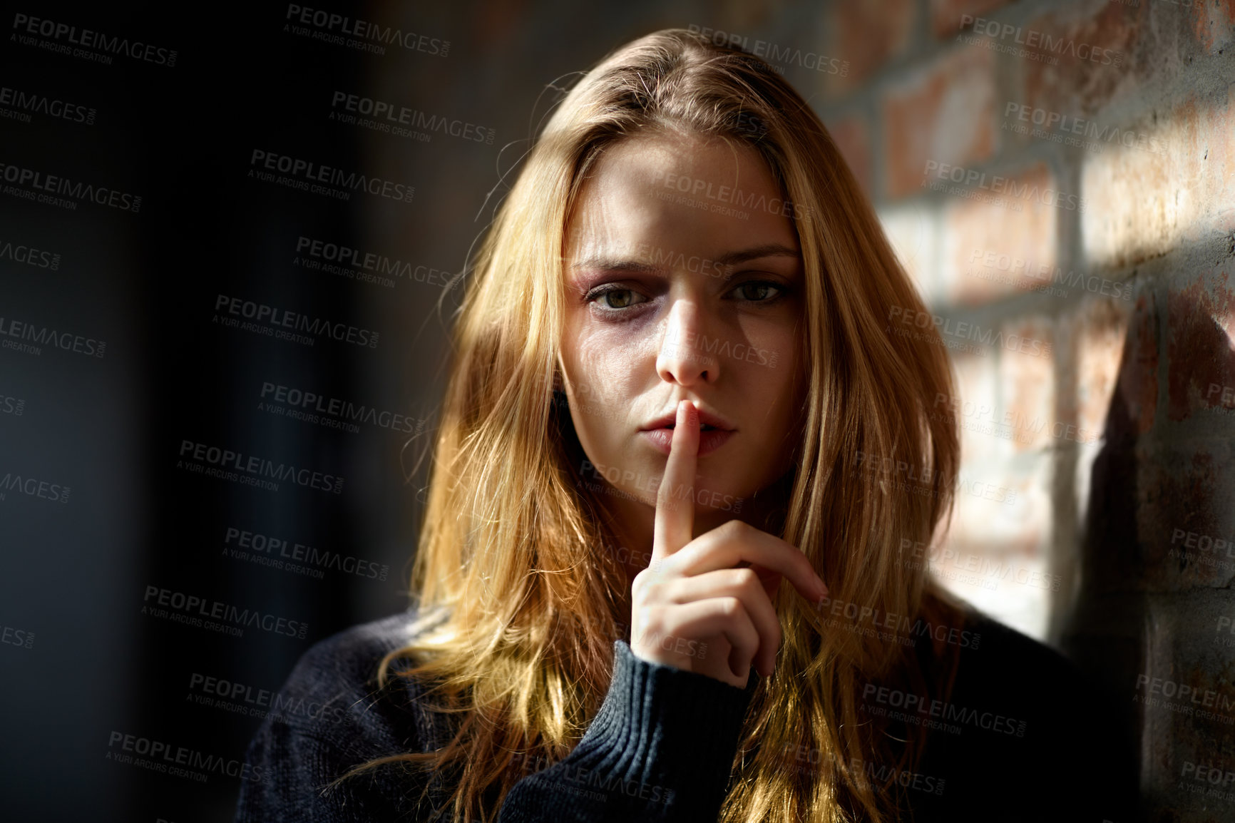 Buy stock photo Abused young woman making a silence gesture while looking at the camera