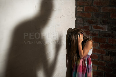 Buy stock photo Abused little girl huddled over while the shadow of her abuser looms towards her