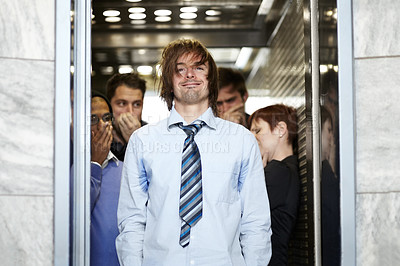 Buy stock photo A dirty young businessman affecting his coworkers in an elevator