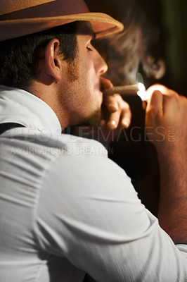 Buy stock photo One man posing against a black background. Vintage man in looking edgy while smoking a cigar. Fashionable young cowboy dressed in a hat with a tobacco addiction. young man taking a break 