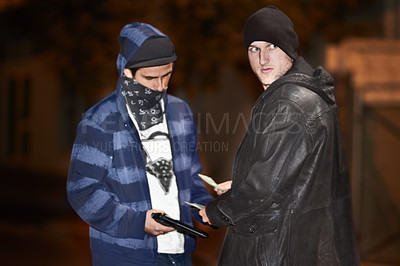 Buy stock photo Two criminals doing a deal transaction while wielding a gun. Two gangster men busy doing illegal activities outside the city. Two hooded suspicious looking men doing a cash transactions at night 