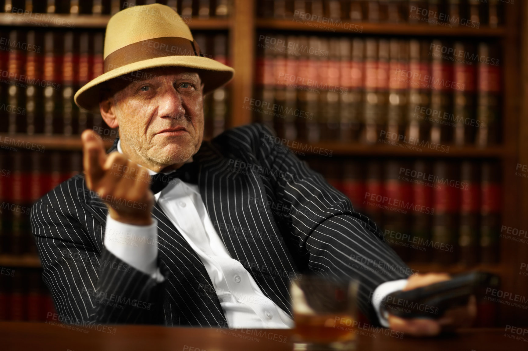 Buy stock photo Aged mob boss wearing a hat and looking serious while pointing
