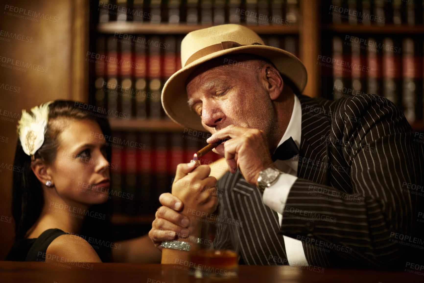 Buy stock photo Mafia, boss and man with cigarette in office, woman and light for smoking. Mature person, godfather and hat in suit for power, reputation and career for criminal activity with tobacco for relaxation