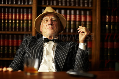 Buy stock photo Portrait, mafia and boss with cigarette in office for habit, smoking or relaxing by desk. Mature, mob leader and retro fashion in suit, bowtie and hat for crime, danger or power with vintage look