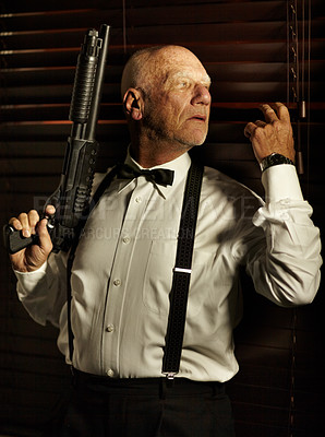 Buy stock photo Mob boss looking out through the blinds while holding a shotgun