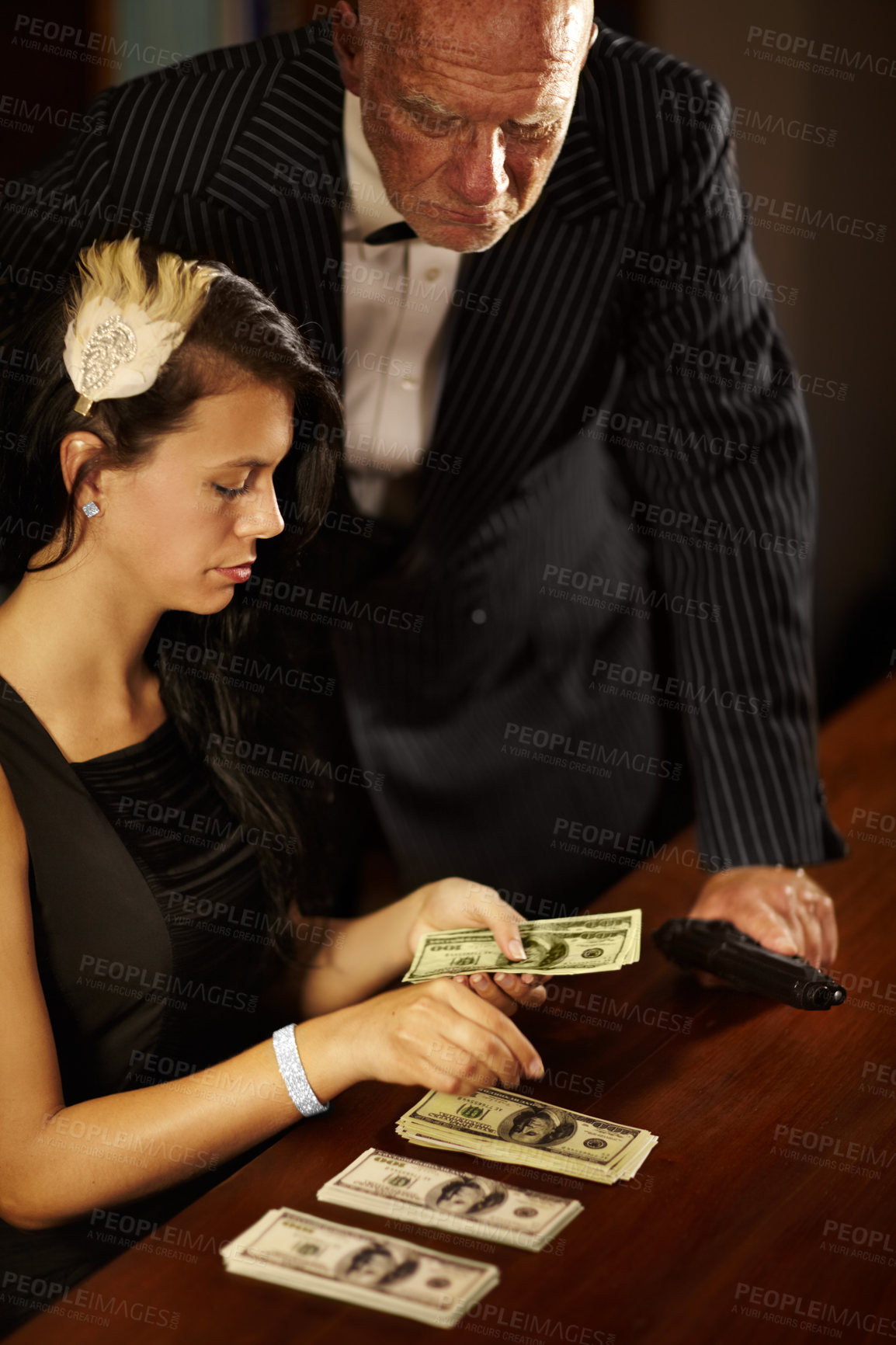 Buy stock photo People, count and money with dollar for mafia in office while mob boss, stand and gun for watching. Young woman, retro and fashion with cash on table, desk and checking of fraud in criminal activity 
