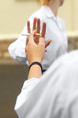 Buy stock photo Cropped shot of a young female studentd turning down cigarettes in response to peer pressure