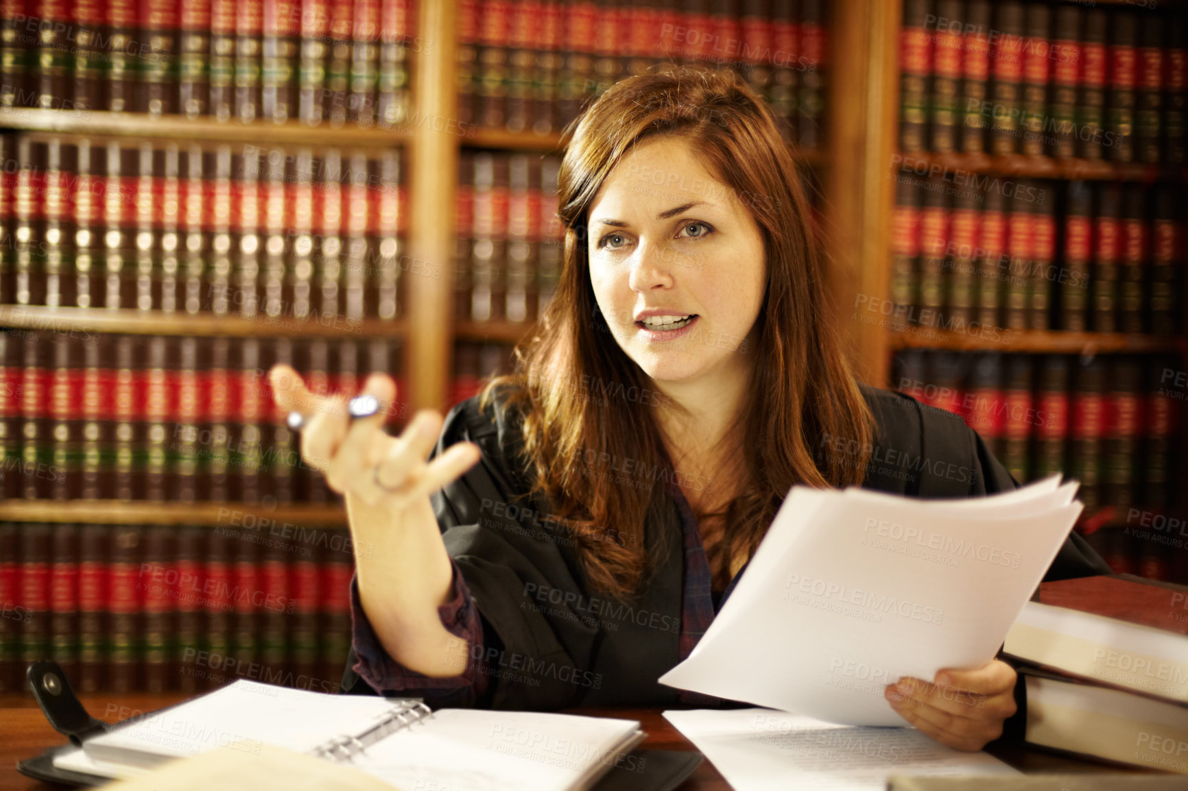 Buy stock photo Attractive young judge sitting at her desk discussing the law