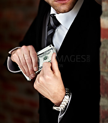Buy stock photo Cropped shot of a man tucking a wad of cash into his jacket