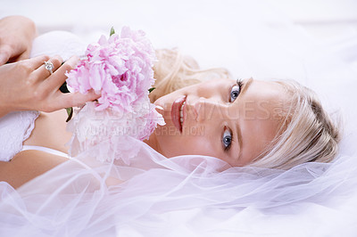 Buy stock photo Closeup portrait of a gorgeous young bride lying on her bed with her bouquet