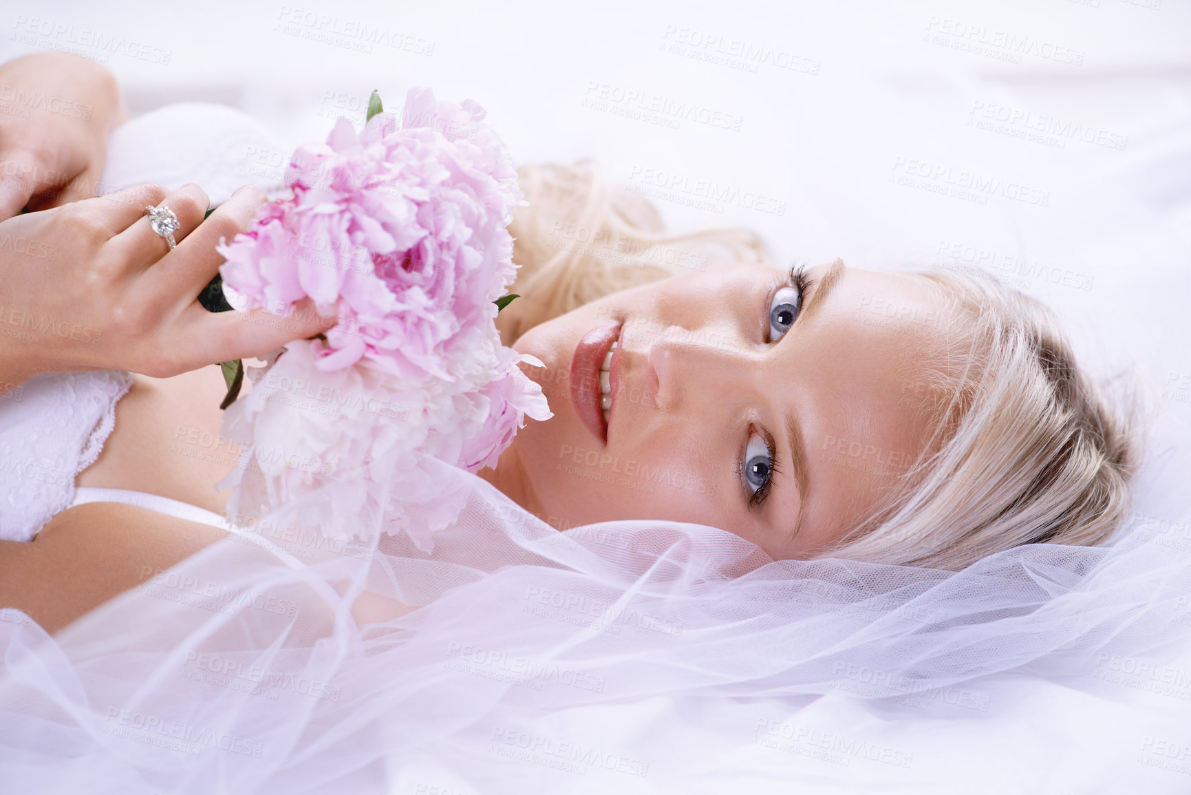 Buy stock photo Closeup portrait of a gorgeous young bride lying on her bed with her bouquet