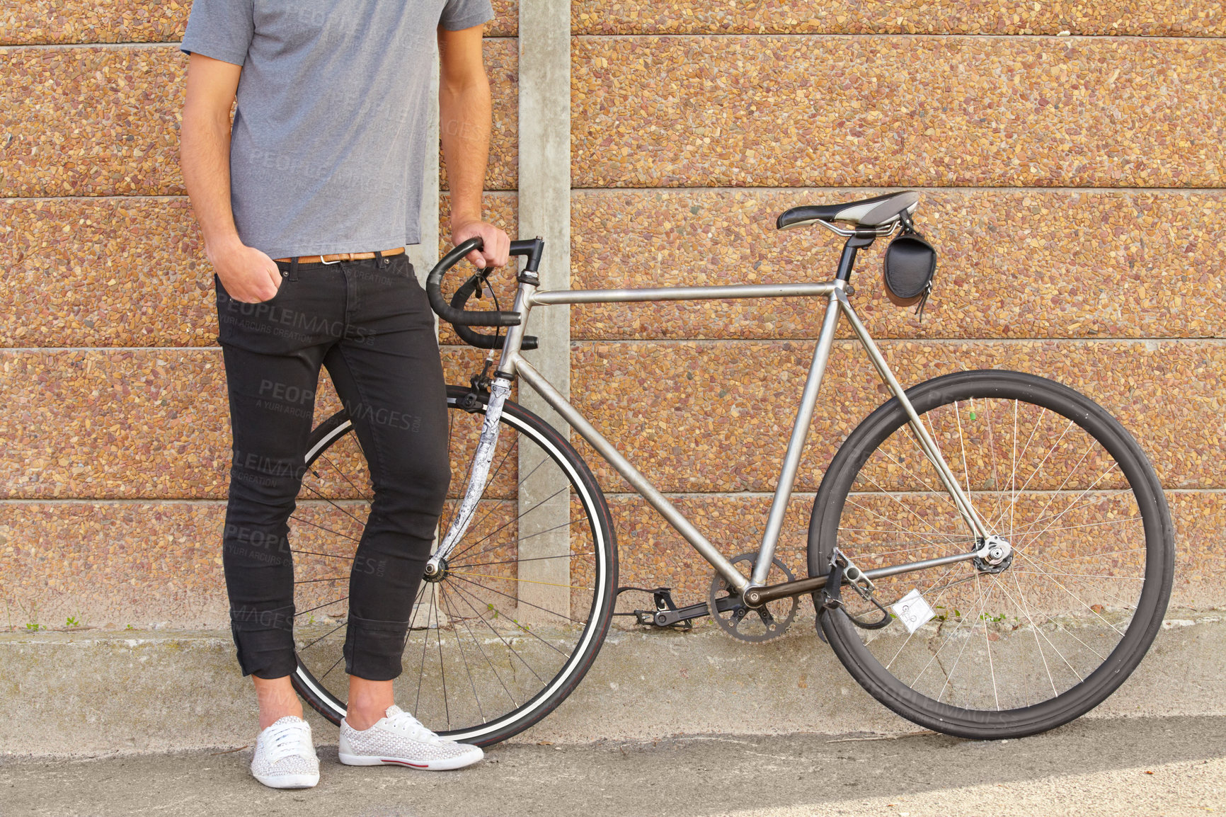 Buy stock photo A cropped shot of a young man standing next to a bicycle