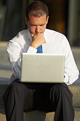 Buy stock photo A thoughtful businessman sitting on the steps and using his laptop