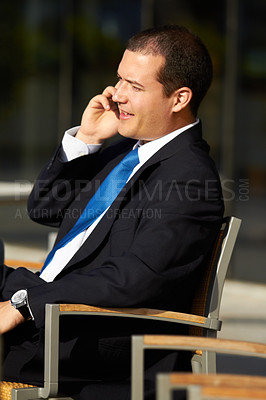 Buy stock photo A businessman sitting on a chair and talking on his cellphone