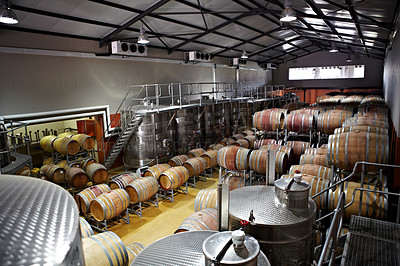 Buy stock photo Wine barrels inside a distillery at a farm. Alcohol brewery filled with fermenting or aging drinks. A whisky cellar of a famous brand. A company using equipment for the process of producing spirits