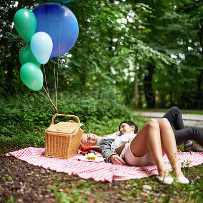 Buy stock photo A young couple relaxing together while on a picnic in a forest
