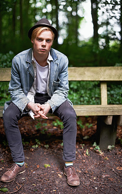 Buy stock photo Portrait of a handsome and stylish young man sitting on a bench in a forest