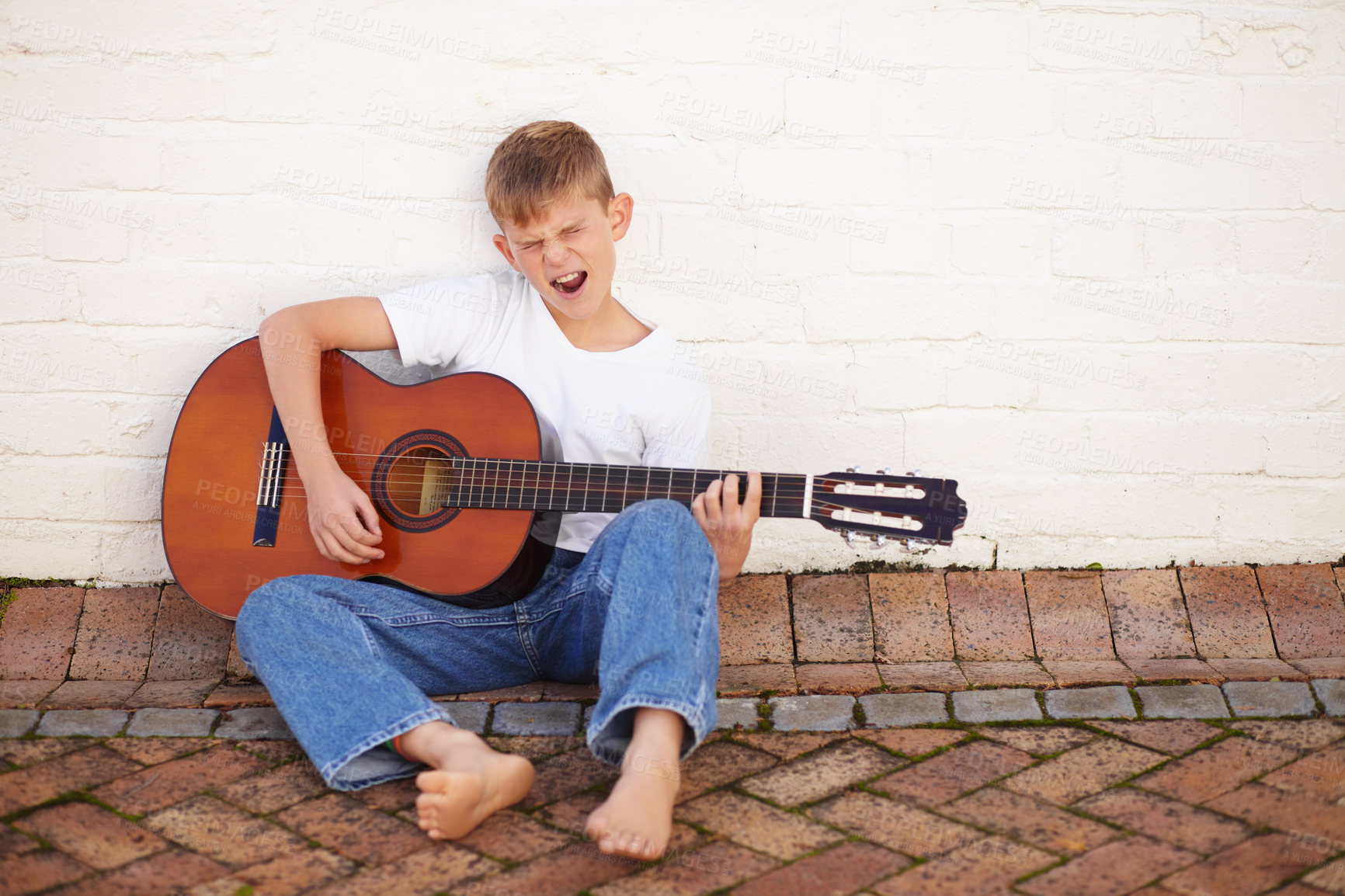 Buy stock photo Young, child and play guitar sing or rock for music lesson, 
talent development or learning skill practice. Male person, school boy or white wall for string acoustic instrument hobby, band or joy