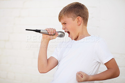 Buy stock photo Young boy lost in song while holding a microphone