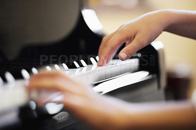 Buy stock photo Closeup of a young boys hands playing the piano diligently. Male pianist playing a song on the piano keys and making classic music. Male child playing on stage or at home