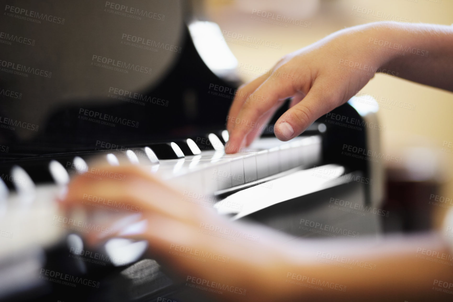 Buy stock photo Closeup of a young boys hands playing the piano diligently. Male pianist playing a song on the piano keys and making classic music. Male child playing on stage or at home