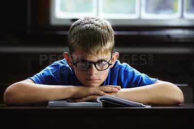 Buy stock photo Kid, school and angry on desk, book and staring for education, adhd and child development. Anxiety, stress and burnout from dyslexia, moody or mental health issue for studying, frustrated and autism