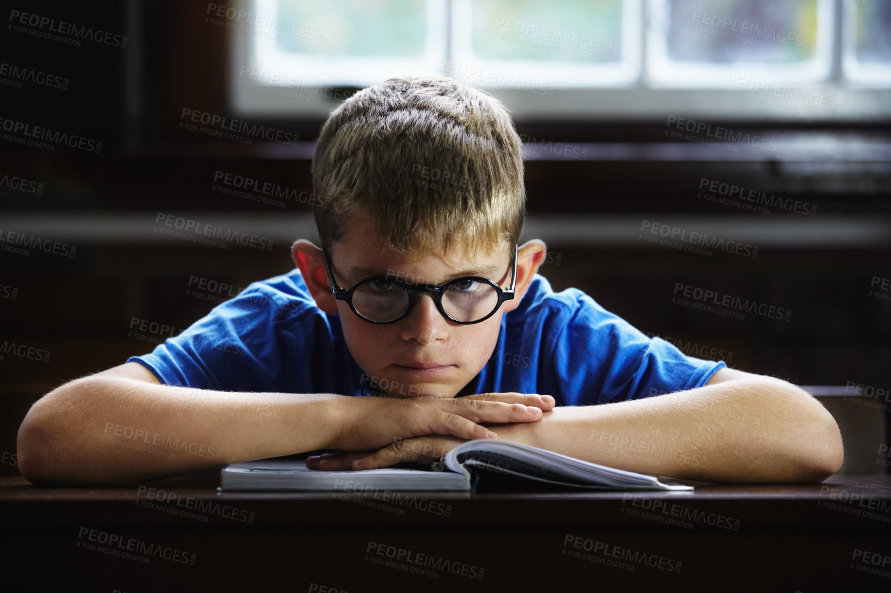 Buy stock photo Kid, school and angry on desk, book and staring for education, adhd and child development. Anxiety, stress and burnout from dyslexia, moody or mental health issue for studying, frustrated and autism