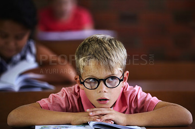 Buy stock photo Classroom, student and boy with thinking, bored and education with glasses, learning and teaching. Kid, school and child with eyewear, development, notebook or tired with a test, morning and studying