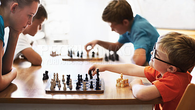 Buy stock photo Young boy wearing spectacles and playing chess with an older child