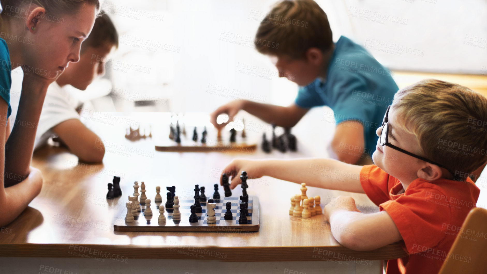 Buy stock photo Young boy wearing spectacles and playing chess with an older child