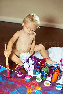 Buy stock photo Creative little baby boy painting with vibrant colors and paints. Small child sitting alone in a diaper and enjoying creative activity at home. Practicing motor skills in fun, artistic activities