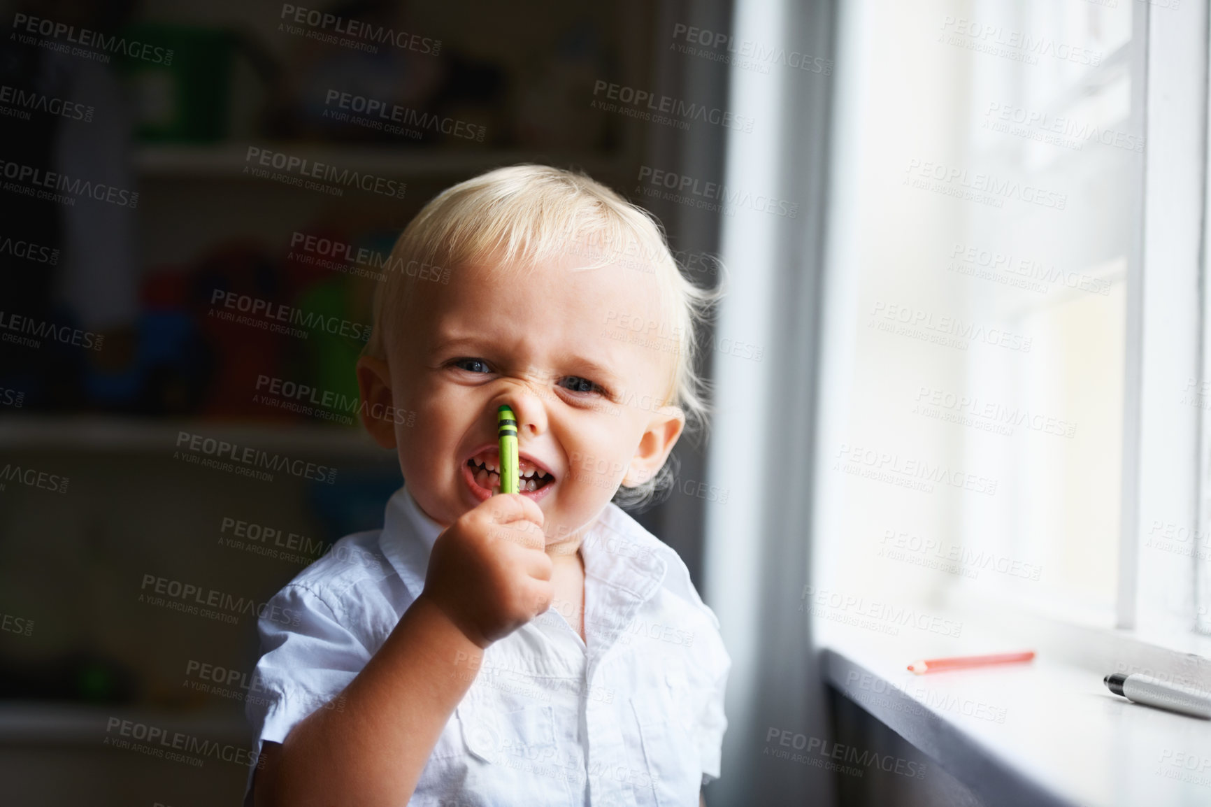 Buy stock photo Portrait of a naughty child holding a crayon up his nose. Playful ADHD baby boy shoving a pencil up his nostril and laughing. Little toddler looking for trouble with a crazy expression on his face