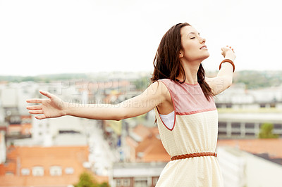 Buy stock photo Gorgeous young woman standing on a rooftop with her arms outstretched