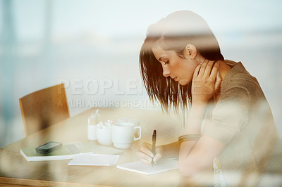 Buy stock photo Attractive young woman journalling in her diary while in a coffee shop