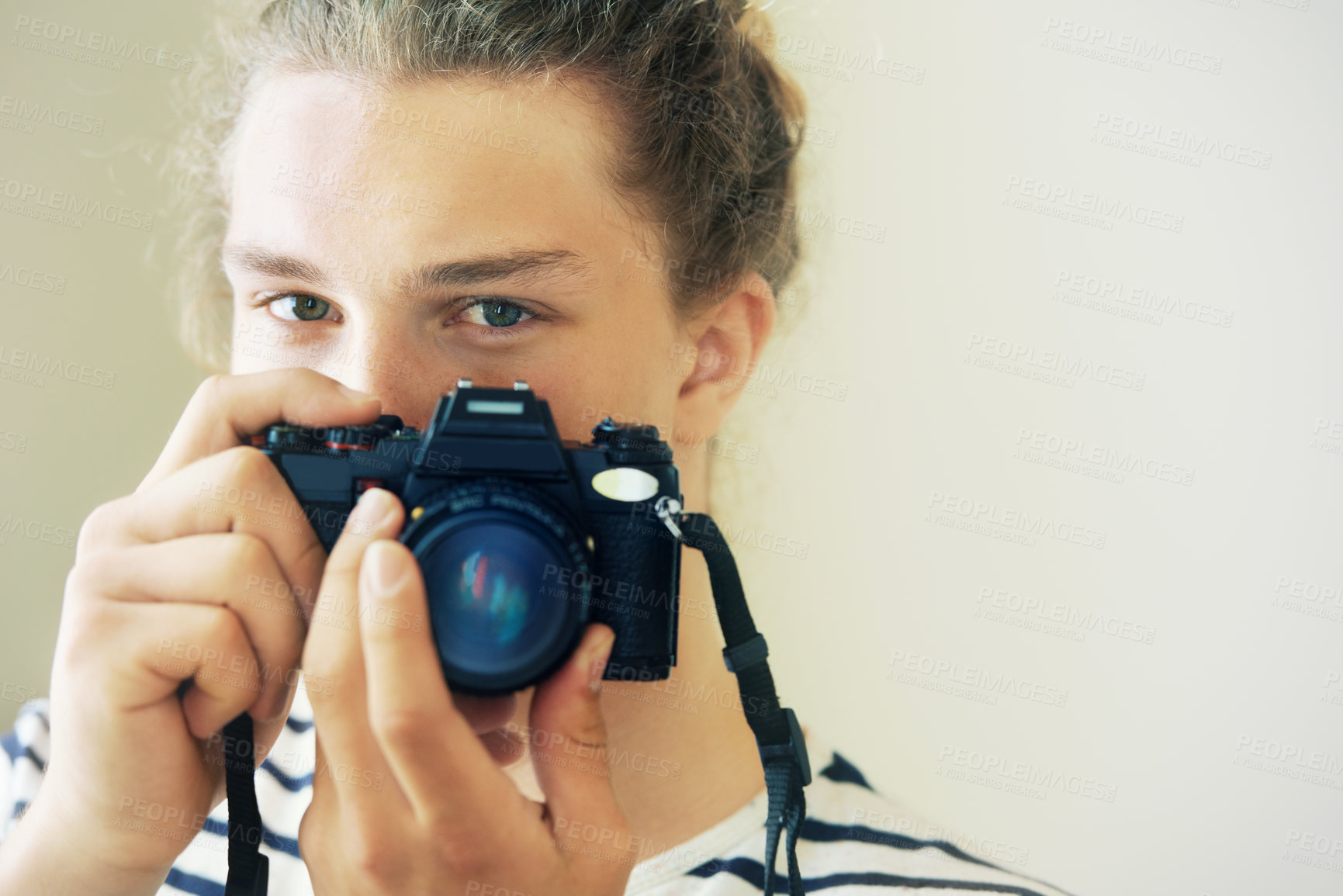 Buy stock photo Young man with his hair in a bun looking at you and holding up his camera
