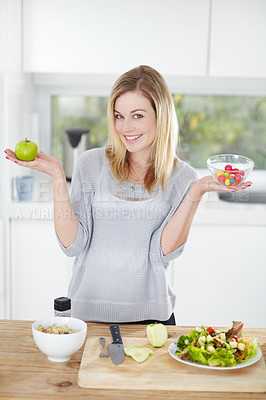 Buy stock photo Choice, sweets and woman decide on healthy food in a kitchen for a diet and holding an apple and candy in home. Portrait, smile an happy female person with fruit for nutrition as lunch meal