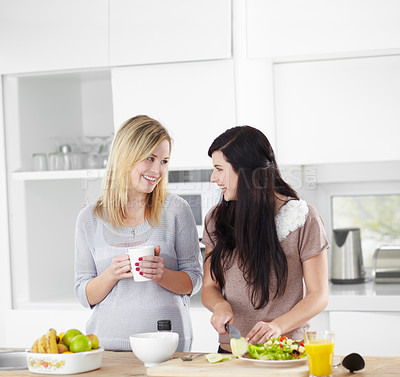 Buy stock photo Two young women making a salad in the kitchen at home