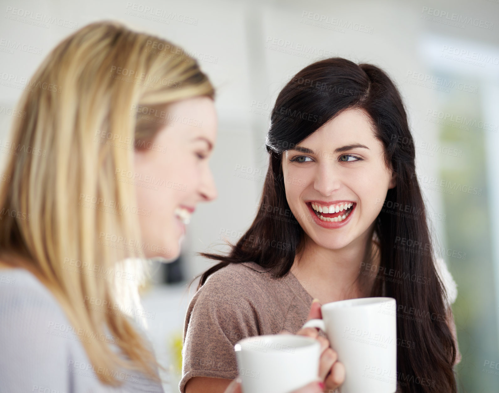 Buy stock photo Two happy young women having coffee together at home