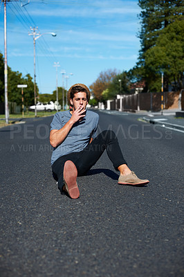 Buy stock photo Cool, man and sitting in the street for smoking, stylish and streetwear fashion. Trendy, young and a person with a cigarette for smoke, tobacco or nicotine habit in the road for youth aesthetic