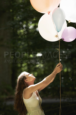 Buy stock photo Woman, holding balloons and fun in nature, playful and outdoors in forest, party decor and celebration for freedom. Female person, sunshine and birthday in park, milestone and achievement for growth