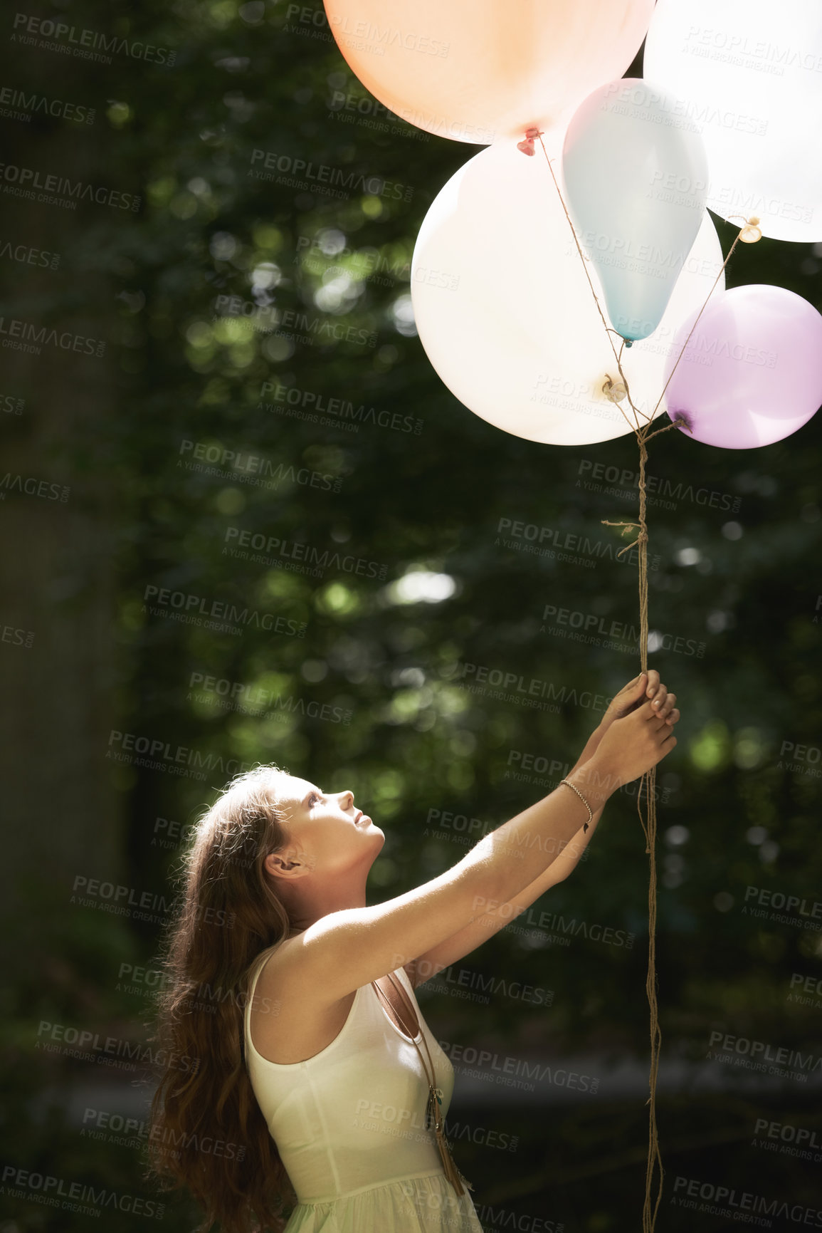 Buy stock photo Woman, holding balloons and fun in nature, playful and outdoors in forest, party decor and celebration for freedom. Female person, sunshine and birthday in park, milestone and achievement for growth