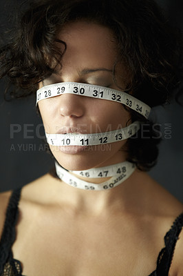 Buy stock photo Mental health. a depressed young woman with tape around face and closed eyes. Depression, a person in a black or dark background and insecure about her body with measurements covering her head.