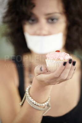 Buy stock photo Cupcake in hand, eating disorder and a woman on diet and tape over mouth to stop or lose weight. Face, covering and restriction of female suffering with anorexia, body dysmorphia or bulimia problem
