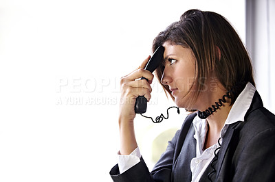 Buy stock photo A bored businesswoman with a phone pressed to her head and the cord wrapped around her neck
