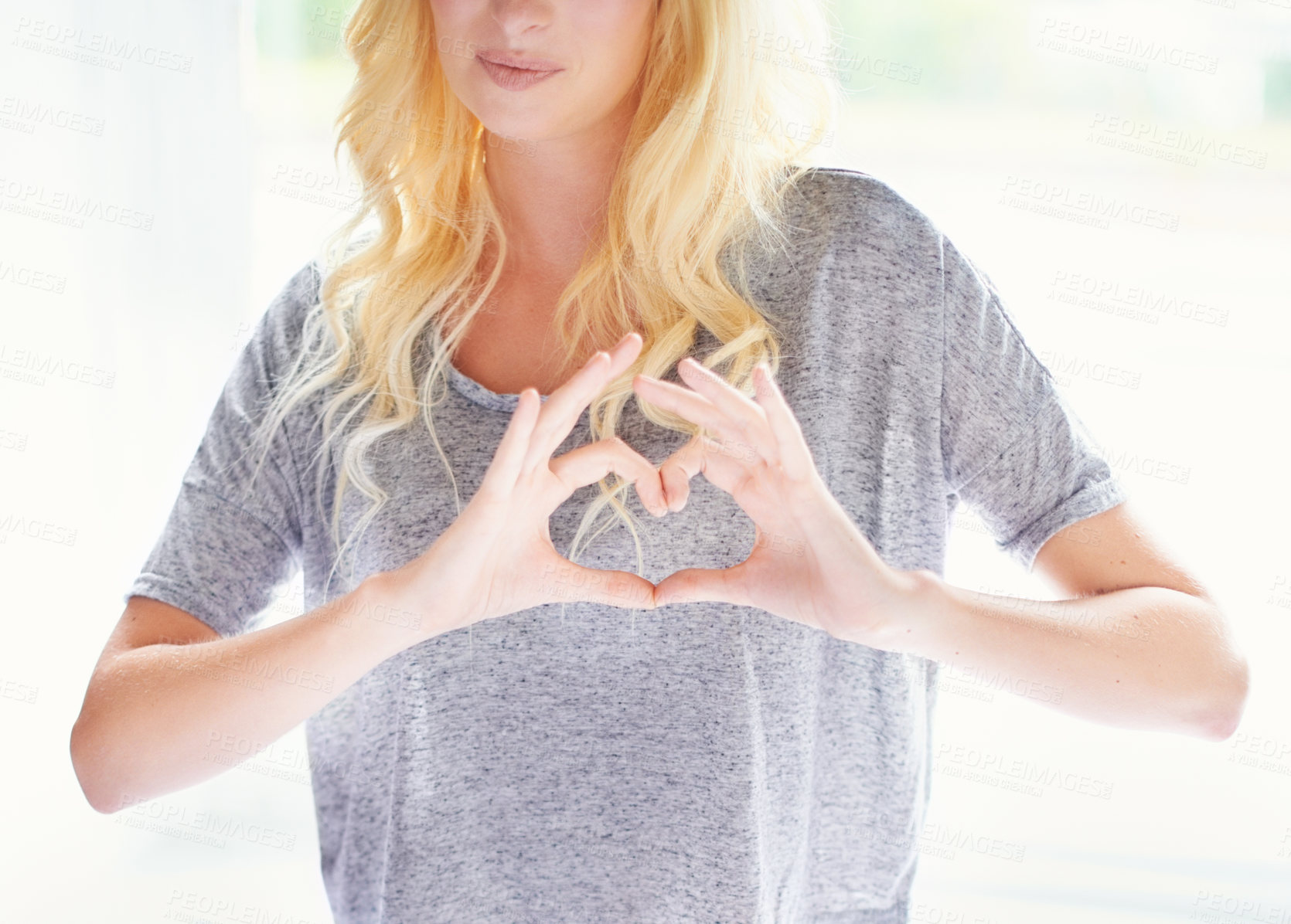 Buy stock photo Cropped image of a gorgeous young woman making a heart gesture