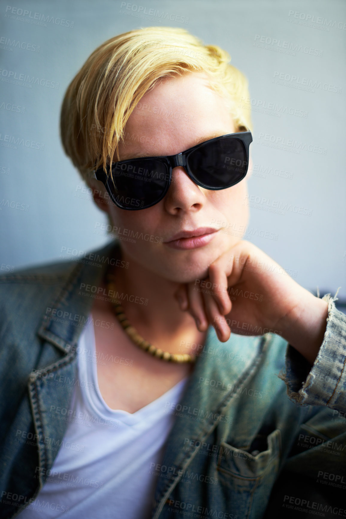 Buy stock photo Attractive young guy wearing hipster shades with his hand on his chin