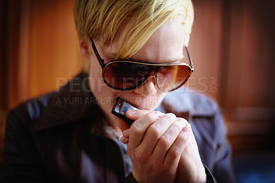 Buy stock photo Attractive young guy in urban wear playing the harmonica