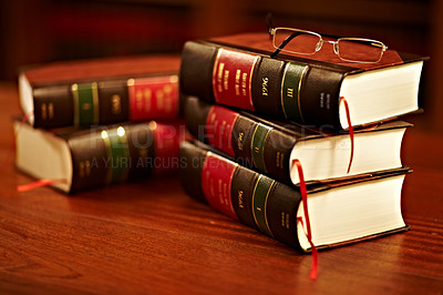 Buy stock photo Shot of a stack of legal books and a pair of glasses on a table in a study