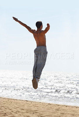Buy stock photo Freedom, beach and man jump at the ocean with energy celebration and positivity on sky background. Rear view, jumping and and male person excited for milestone, success and achievement in nature